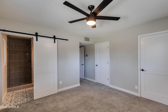 unfurnished bedroom with baseboards, a barn door, visible vents, and light colored carpet