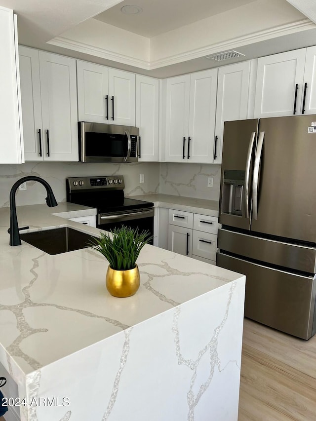 kitchen with light stone countertops, sink, light hardwood / wood-style floors, stainless steel appliances, and white cabinets