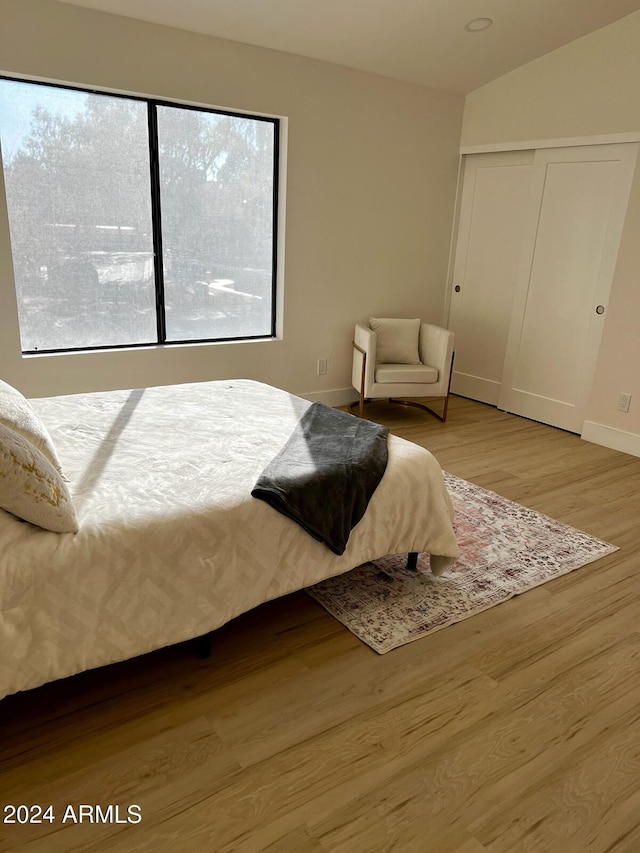 bedroom featuring a closet, hardwood / wood-style flooring, and lofted ceiling