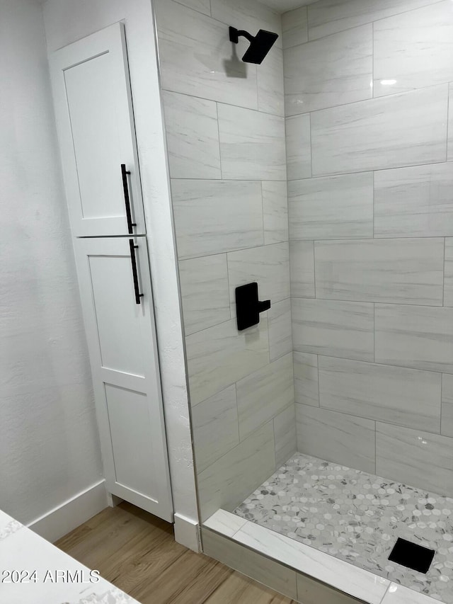 bathroom with hardwood / wood-style flooring and tiled shower