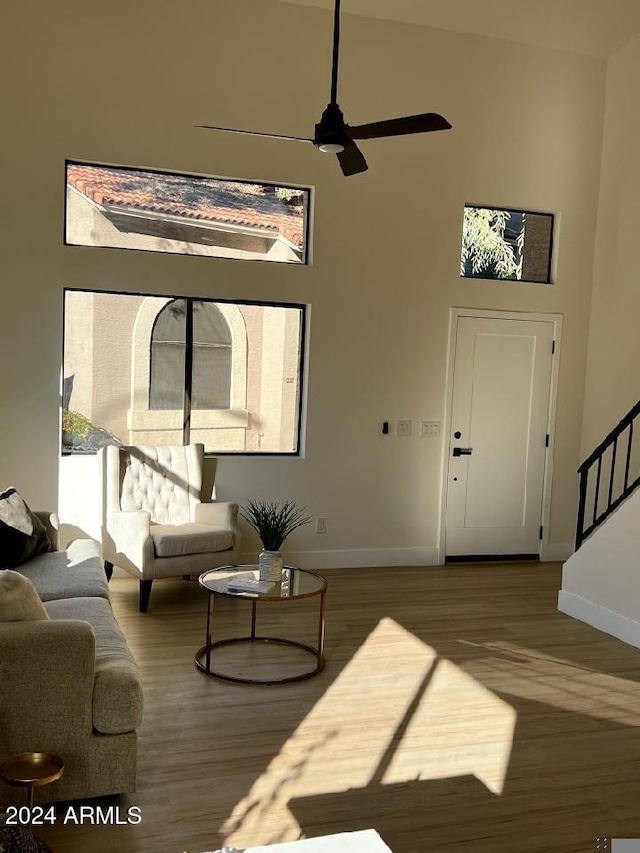 living room featuring a towering ceiling, hardwood / wood-style flooring, and ceiling fan