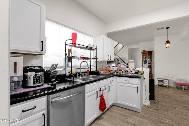 kitchen featuring white cabinetry, stainless steel dishwasher, sink, and pendant lighting