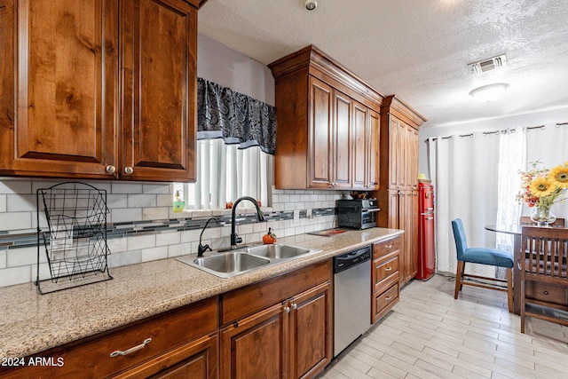 kitchen with backsplash, a textured ceiling, light stone countertops, stainless steel dishwasher, and sink