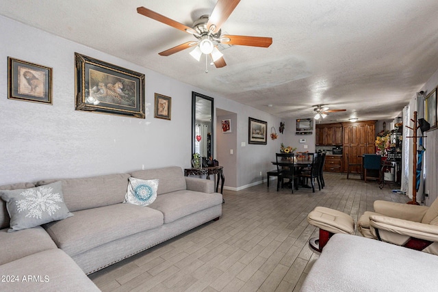 living room featuring ceiling fan, a textured ceiling, and light hardwood / wood-style flooring