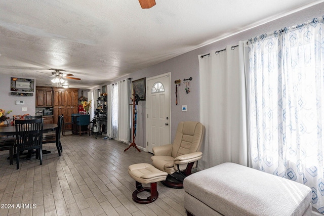 living room featuring a textured ceiling, light hardwood / wood-style floors, and ceiling fan