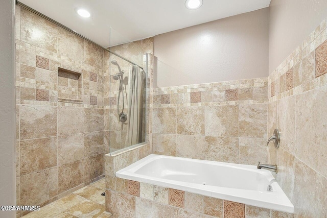 bathroom featuring tile walls and independent shower and bath