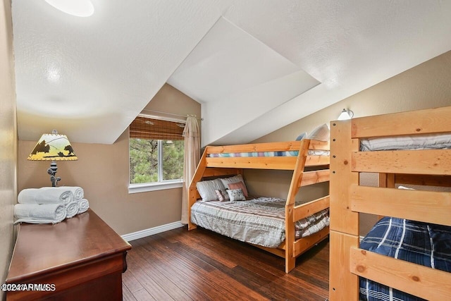 bedroom with a textured ceiling, vaulted ceiling, and dark hardwood / wood-style flooring