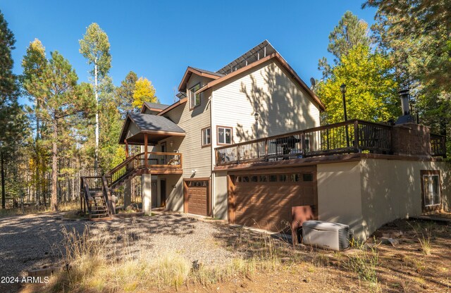 rear view of property with central AC, a garage, and a wooden deck