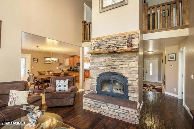 living room with a high ceiling, hardwood / wood-style floors, and a stone fireplace