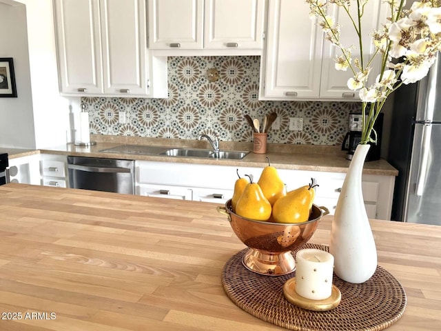 kitchen featuring butcher block countertops, a sink, white cabinetry, appliances with stainless steel finishes, and decorative backsplash