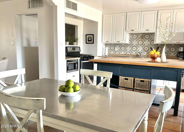 kitchen featuring visible vents, backsplash, appliances with stainless steel finishes, and wood counters