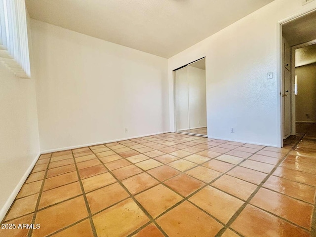 tiled empty room featuring baseboards