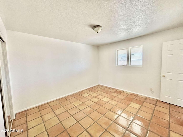 unfurnished room featuring baseboards, a textured ceiling, and light tile patterned flooring