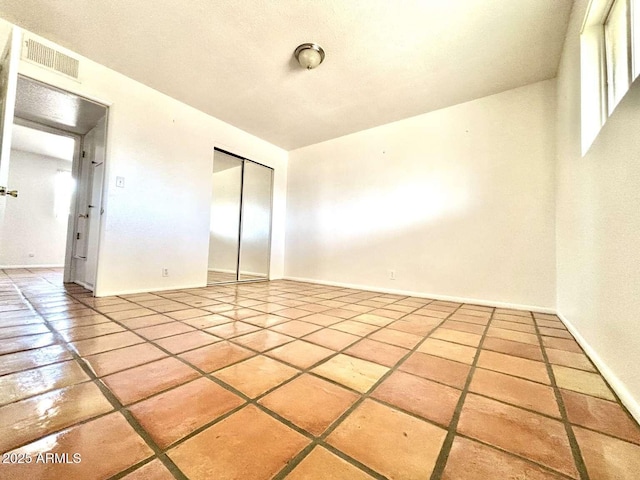 unfurnished room featuring tile patterned flooring, baseboards, and visible vents