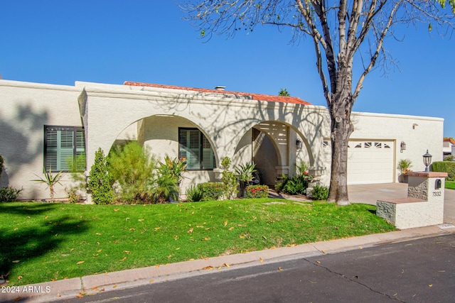 mediterranean / spanish home featuring a front yard and a garage