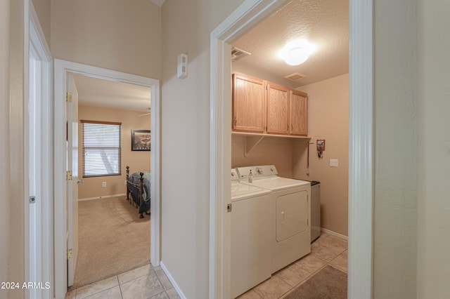 washroom featuring independent washer and dryer, cabinets, light tile patterned floors, and a textured ceiling