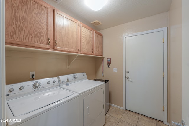 washroom with cabinets, light tile patterned floors, washing machine and dryer, and a textured ceiling