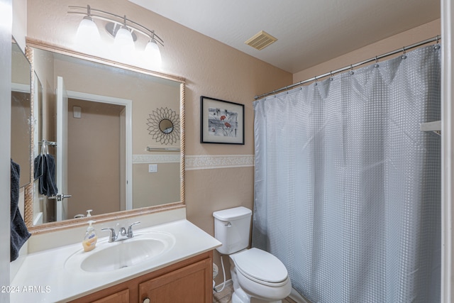 bathroom featuring curtained shower, vanity, and toilet