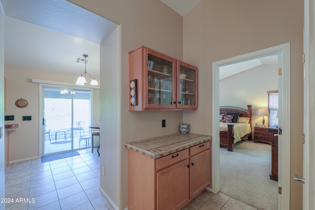 kitchen with a notable chandelier, light colored carpet, lofted ceiling, and hanging light fixtures