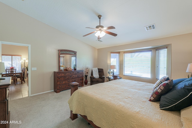 carpeted bedroom featuring vaulted ceiling, multiple windows, and ceiling fan