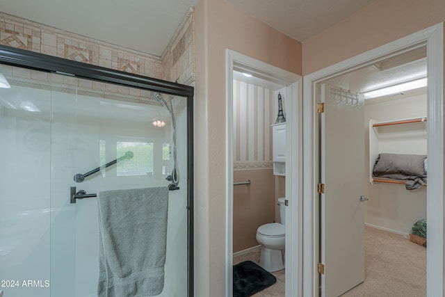 bathroom featuring toilet and a shower with door