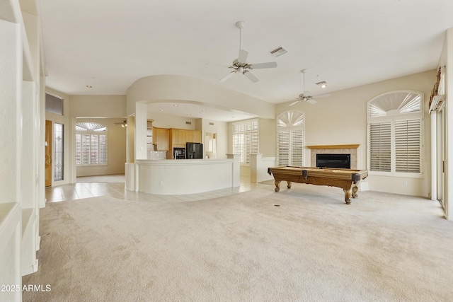 unfurnished living room with a tile fireplace, light colored carpet, ceiling fan, and billiards