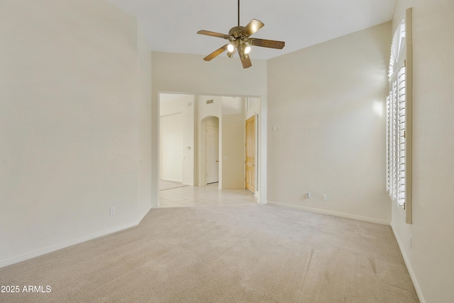 unfurnished room featuring a towering ceiling, light carpet, and ceiling fan