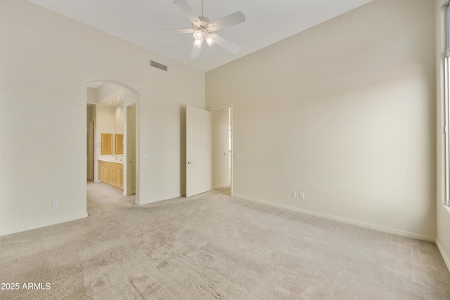 empty room with light carpet, a towering ceiling, and ceiling fan