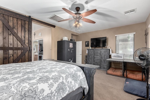 bedroom with a barn door, ceiling fan, a closet, and light carpet