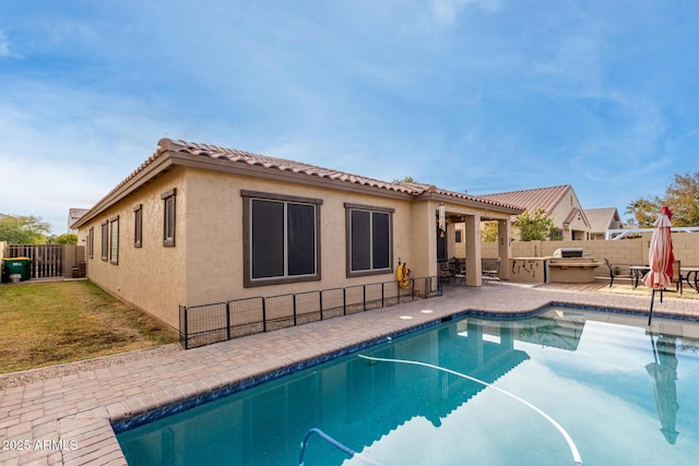 view of pool with exterior kitchen and a patio