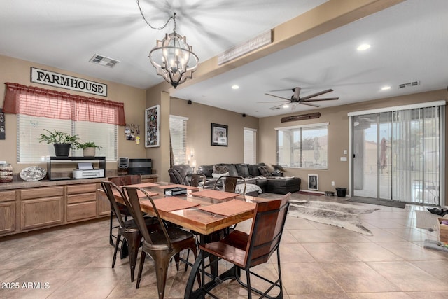 dining room with light tile patterned floors and ceiling fan with notable chandelier