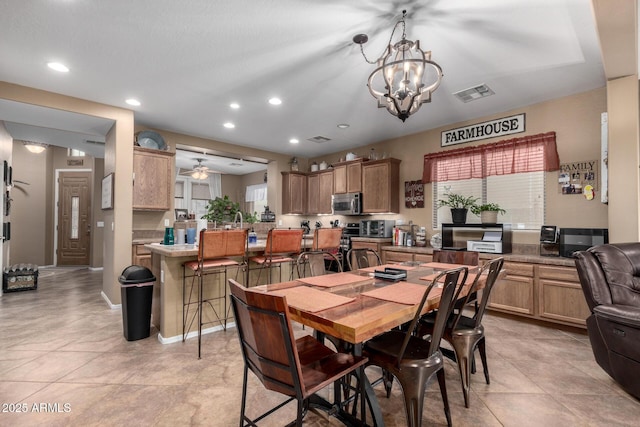 tiled dining area with ceiling fan with notable chandelier and a healthy amount of sunlight