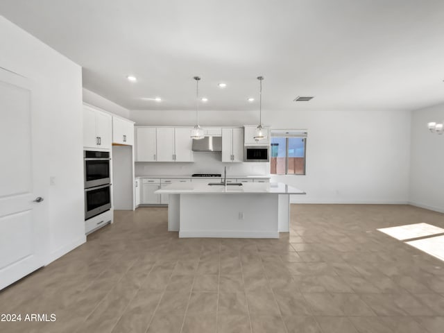 kitchen featuring a kitchen island with sink, white cabinetry, and hanging light fixtures