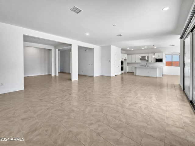 unfurnished living room with sink and light tile patterned flooring