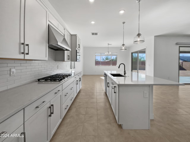 kitchen featuring appliances with stainless steel finishes, extractor fan, sink, a center island with sink, and hanging light fixtures