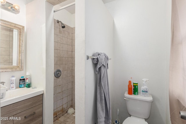 bathroom featuring vanity, a tile shower, and toilet