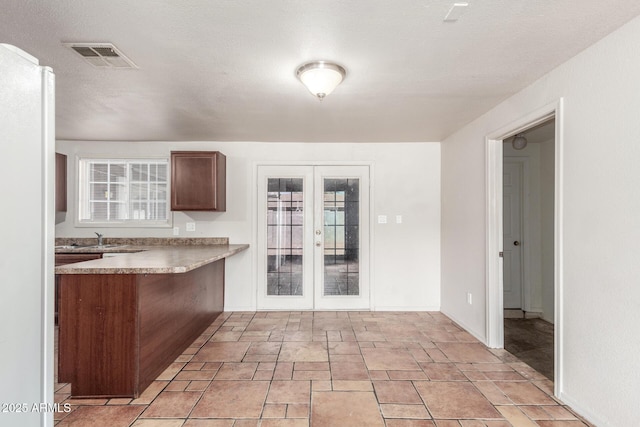 kitchen with french doors, kitchen peninsula, and sink