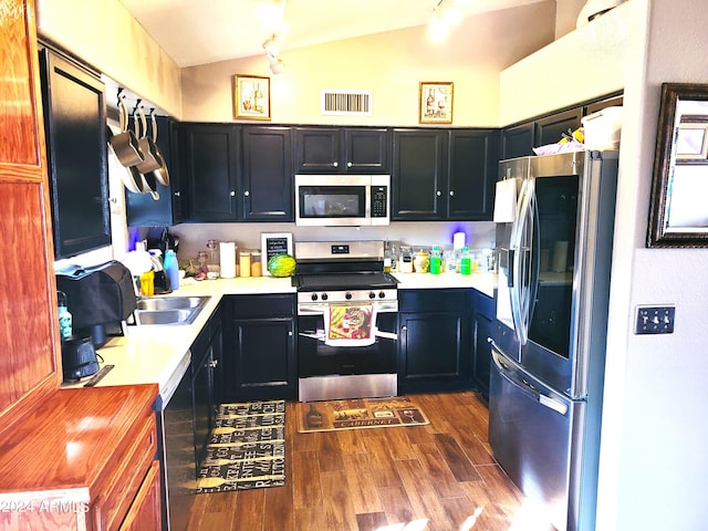 kitchen with sink, stainless steel appliances, dark wood-type flooring, and vaulted ceiling