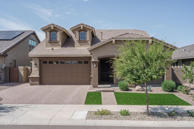 view of front of house with stucco siding, a garage, a tiled roof, and decorative driveway