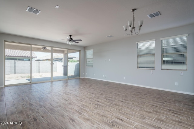 empty room with wood-type flooring and ceiling fan with notable chandelier