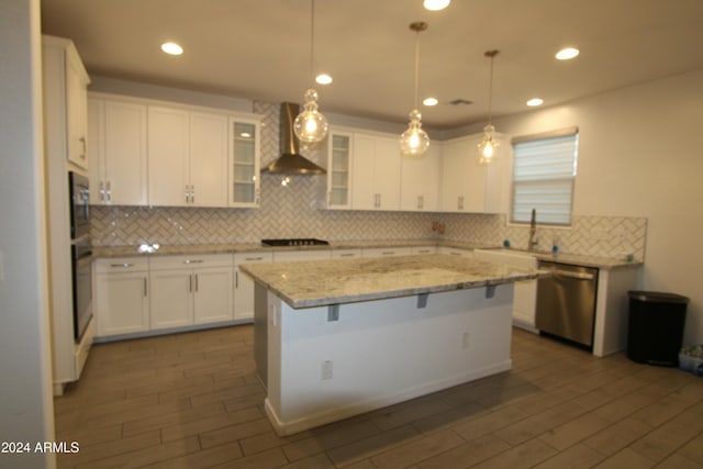 18813 W Solano Dr, Litchfield Park, AZ 85340 - kitchen featuring dishwasher, wall chimney exhaust hood, white cabinets, tasteful backsplash, and a center island