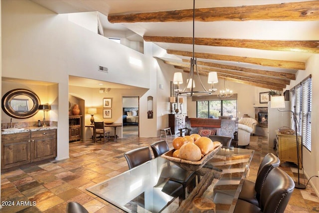 dining area with beam ceiling, sink, a notable chandelier, and a towering ceiling