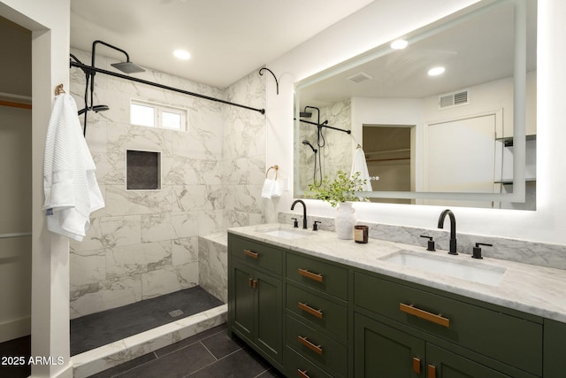 bathroom with visible vents, a tile shower, and a sink