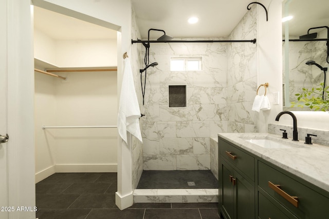 bathroom featuring vanity, baseboards, a stall shower, a walk in closet, and tile patterned floors