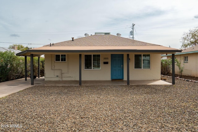 bungalow-style house with concrete block siding, covered porch, and roof with shingles