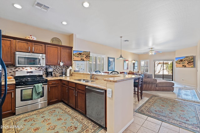 kitchen featuring tasteful backsplash, stainless steel appliances, kitchen peninsula, and ceiling fan