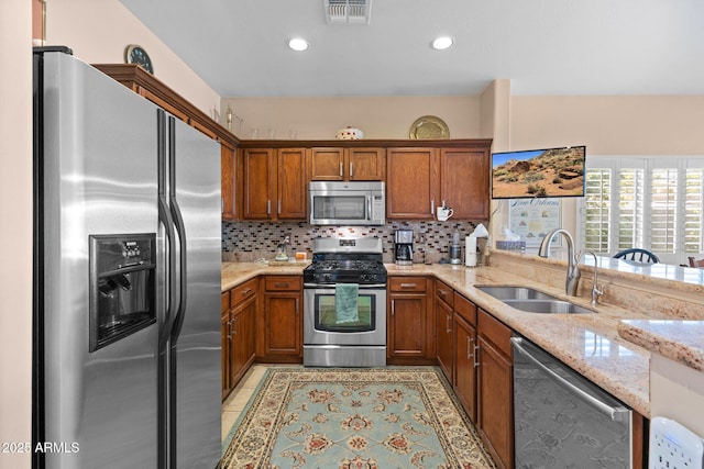 kitchen featuring appliances with stainless steel finishes, light stone countertops, light tile patterned floors, decorative backsplash, and sink