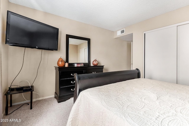 bedroom featuring a textured ceiling, light colored carpet, visible vents, baseboards, and a closet