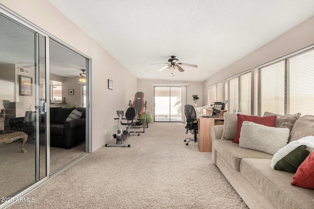 living area with a textured ceiling, carpet floors, ceiling fan, and visible vents