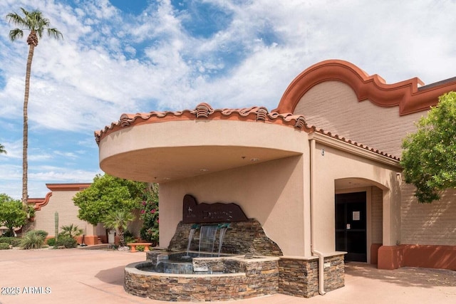 exterior space featuring a tiled roof and stucco siding